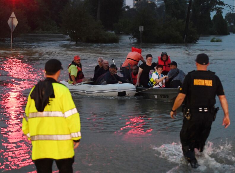 People are rescued from a hotel by boat after Hurricane Harvey caused heavy flooding in Houston, Texas on August 27, 2017. 
Massive flooding unleashed by deadly monster storm Harvey left Houston -- the fourth-largest city in the United States -- increasingly isolated as its airports and highways shut down and residents fled homes waist-deep in water. / AFP PHOTO / MARK RALSTON        (Photo credit should read MARK RALSTON/AFP/Getty Images)
