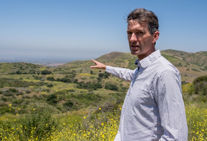 A man standing pointing at some hills.