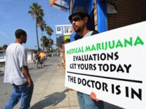 A man holds a placard advertising medical marijuana outside an evaluation clinic on Venice Beach in Los Angeles on October 9, 2009.
