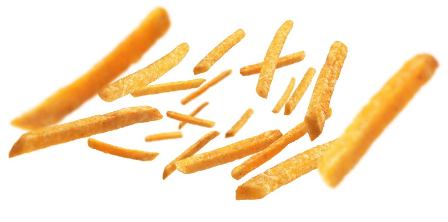 A photo illustration of golden brown French fries levitating on a white background.