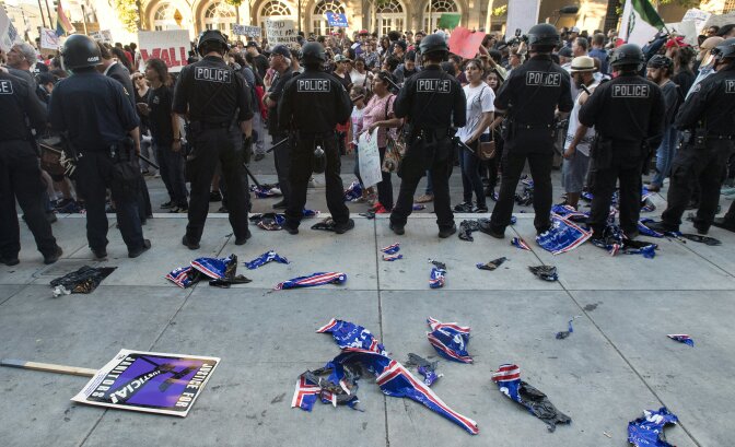 Torn Trump signs are seen on the ground behind a police skirmish line during a protest near where Republican presidential candidate Donald Trump held a rally in San Jose, California on June 2, 2016. 
Protesters attacked Trump supporters as they left the rally, burned an american flag, trump paraphernalia and scuffled with police and each other.