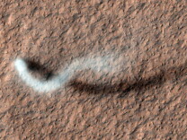 A smoky trail is visible in a serpentine shape against a red surface