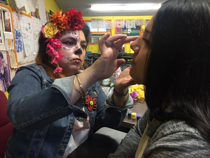 Art and english teacher Learsi Martinez paints a red flower on the face of 17-year-old Jocelyn Cordova. Cordova, who lost her sister, says her sister loved red and flowers.  