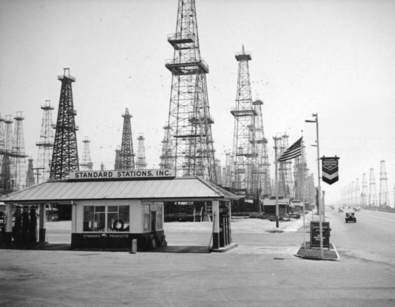 A small gas station sits in front of dozens of oil wells.