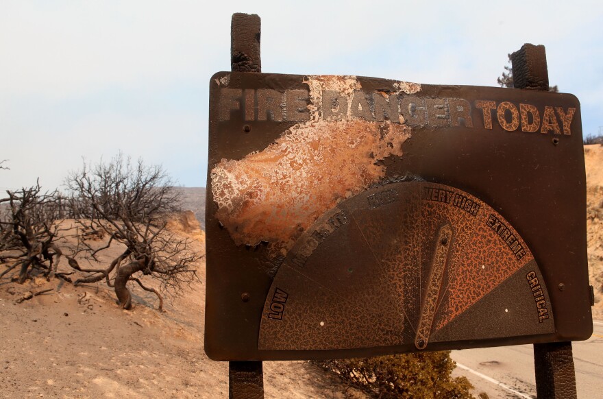 A charred sign shows fire danger as very high