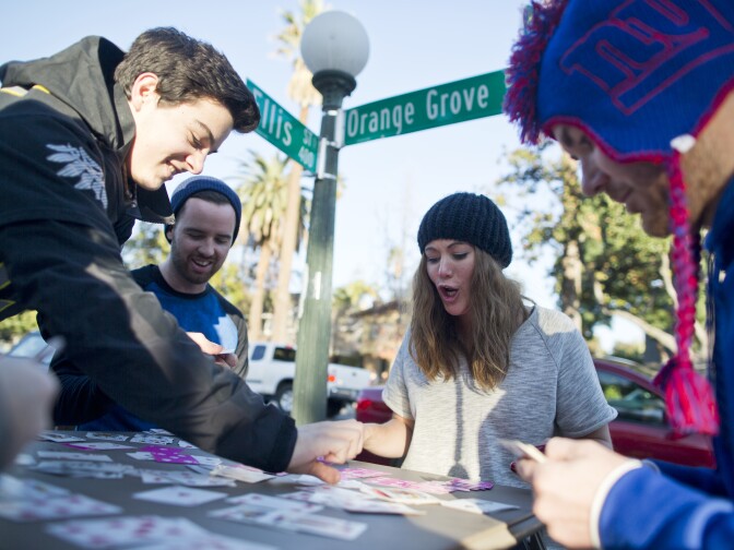 Quincy Gunther of Eugene, Ore., left, Adam Castro of San Jose and Whitney and Ben Wood of La Crescenta play cards while camping out on Orange Grove Boulevard in Pasadena on Wednesday afternoon, Dec. 31, 2014 before the 2015 Rose Parade. The group of Oregon fans have been camping since 11:30 a.m. on Wednesday.