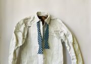 A potrait of a fake men's white dress shirt and blue stripped tie on a flat white surface. The shirt appears short and crumpled since it's made with paper.