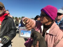 Serena Welch holds up an Orange County-issued ID card as she waits in line for a motel voucher on Tuesday morning, Feb. 20, 2018.