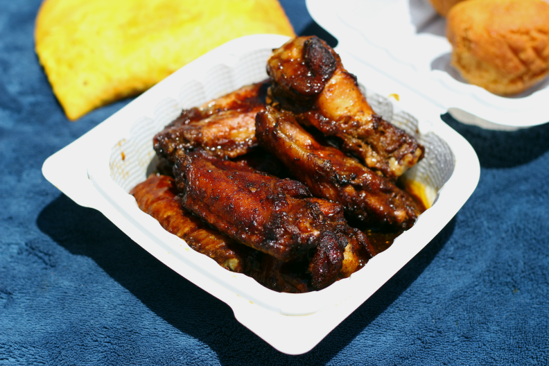 a plastic container of charred chicken wings