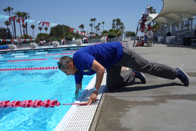                                Juan Garcia of the Long Beach Environmental Health Department takes a sample of water to test for residual chlorine at Belmont Pool in Long Beach June 7, 2018. (Photo by Sharon McNary/KPCC)