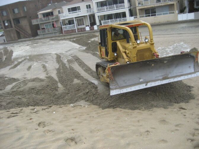 Bulldozers reinforce sand berm in Seal Beach