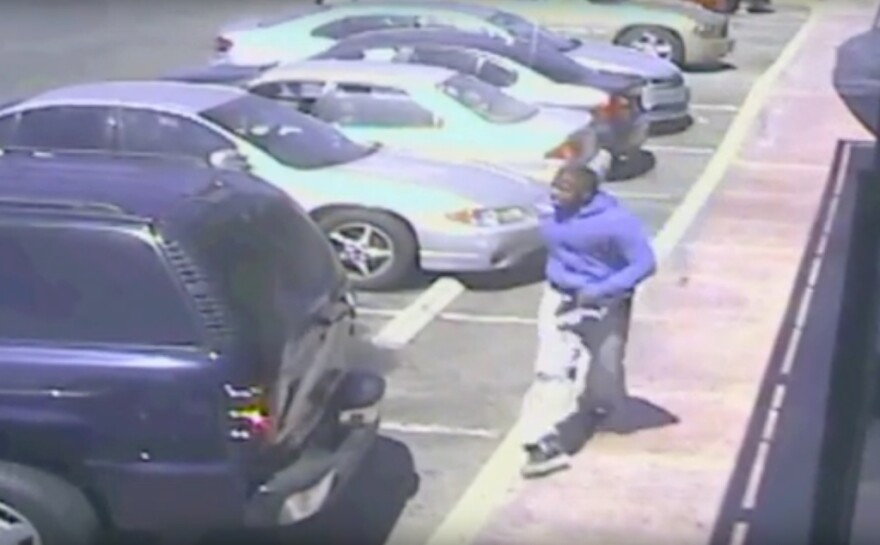 In a screenshot from a security camera video released by the Los Angeles Police Department, a man can be seen holding what appears to be a handgun in his left hand.