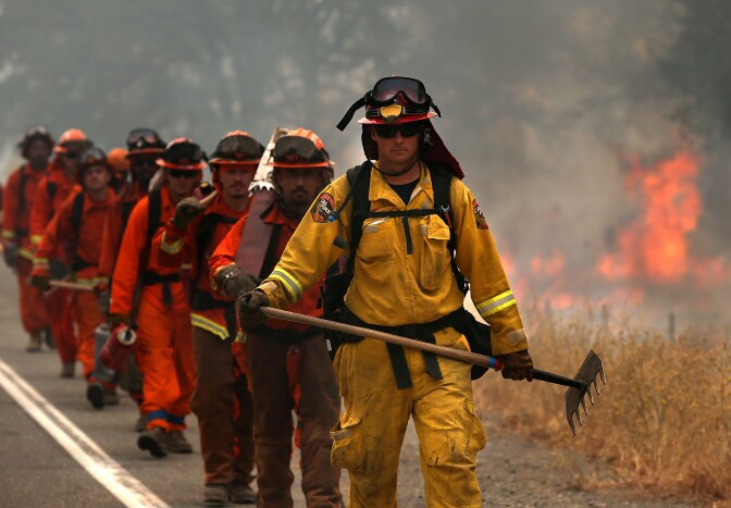 A Cal Fire firefighter leads a group of inmate firefighters during a burn operation to head off the Rocky Fire on August 2, 2015 near Clearlake, California.