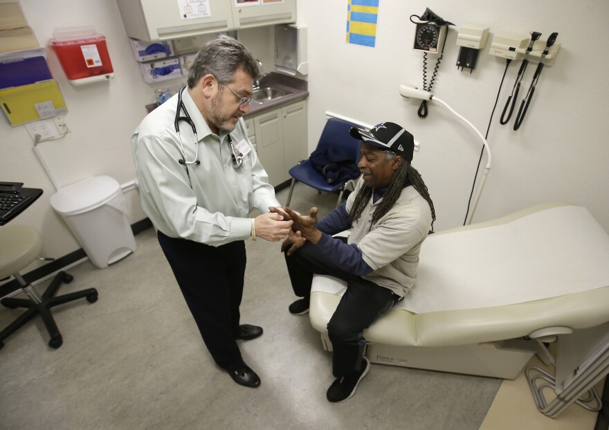 FILE - In this Feb. 18, 2016 file photo, Doctor Leonid Basovich, left, examines Medi-Cal patient Michael Epps, at the WellSpace Clinic in Sacramento, Calif. Gov. Jerry Brown is at odds with Legislative Democrats over how to spend the money raised from the $2 a pack tax increase on tobacco, approved by voters when the they passed Proposition 56 last year. Democratic lawmakers want to give incentives to doctors and dentists that take on more Medi-Cal patients while Brown proposes using the $1.2 billion to pay for normal growth in Medi-Cal. (AP Photo/Rich Pedroncelli, File)