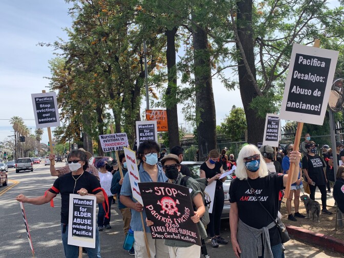 Protesters outside Sakura Gardens hold signs opposing the proposed closure of the facility.