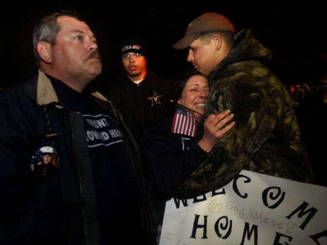 Steve Posey (left), father of Lance Cpl. Gregory Posey, who died in combat, stands stoic as the buses arrive bringing his son's company back to Camp Lejeune. His wife, Delma, breaks down in the arms of a friend.