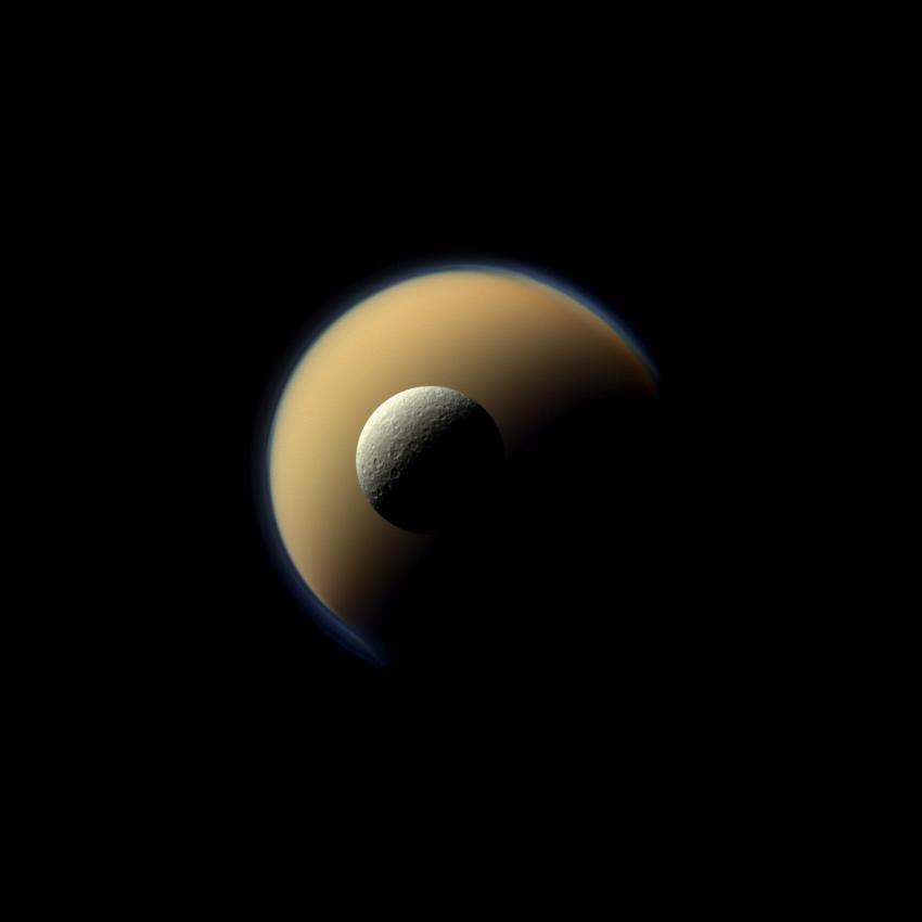 Saturn's largest and second largest moons, Titan and Rhea, appear to be stacked on top of each other in this true-color scene from NASA's Cassini spacecraft. The north polar hood can be seen on Titan (3,200 miles across) appearing as a detached layer at the top of the moon on the top right. Images taken using red, green and blue spectral filters were combined to create this natural-color view. The images were acquired with Cassini's narrow-angle camera on June 16, 2011, at a distance of approximately 1.1 million miles.