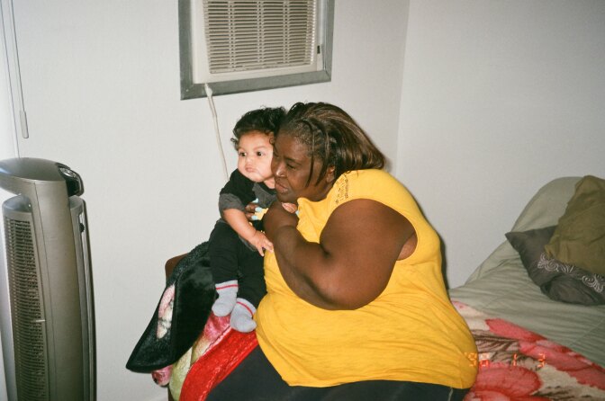 Nikidda's mother holds Hunter on a bed.