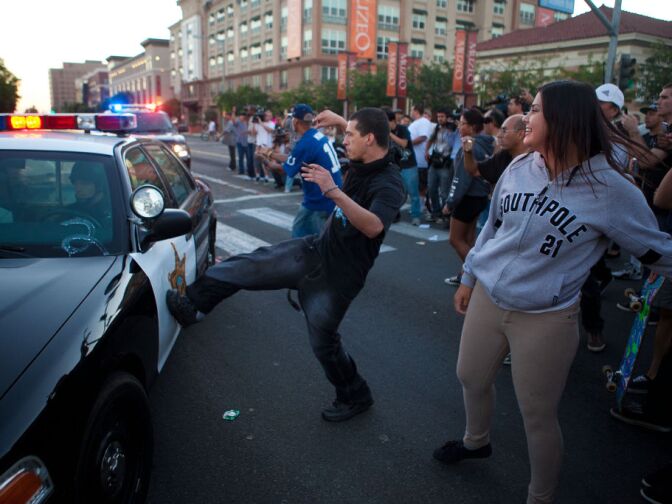 ANAHEIM, CA - JULY 24: A protester kicks a passing police car during a demonstration to show outrage for the shooting death of Manuel Angel Diaz, 25, at Anaheim City Hall on July 24, 2012 in Anaheim, California. Diaz was fatally shot July 21 by an Anaheim police officer and has sparked days of protests by the angered community. (Photo by Jonathan Gibby/Getty Images)
