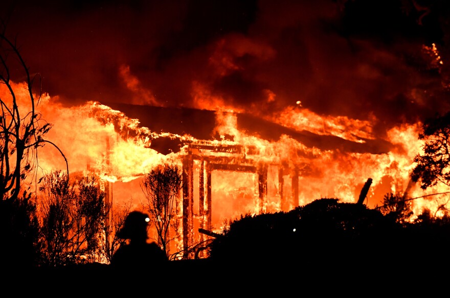 TOPSHOT - Firefighters assess the scene as a house burns in the Napa wine region of California on October 9, 2017, as multiple wind-driven fires continue to ravage the area burning structures and causing widespread evacuations.  / AFP PHOTO / JOSH EDELSON        (Photo credit should read JOSH EDELSON/AFP/Getty Images)