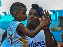 Dodgers player Yasiel Puig holds his nephew during a children's baseball training session in Havana, Cuba on December 16, 2015.