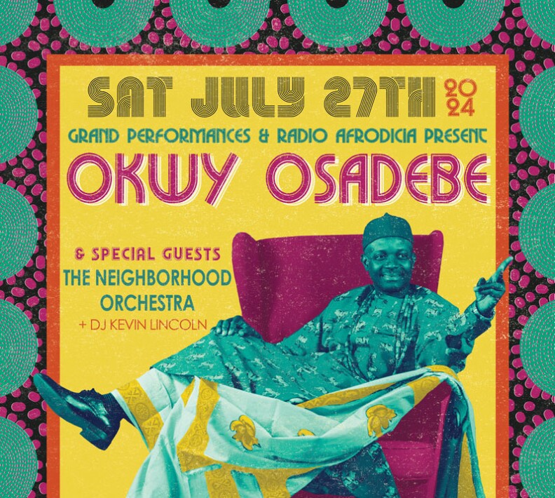 Artist Okwy Osadebe sits on a chair with one leg raised over the arm rest. He points the other direction while smiling.