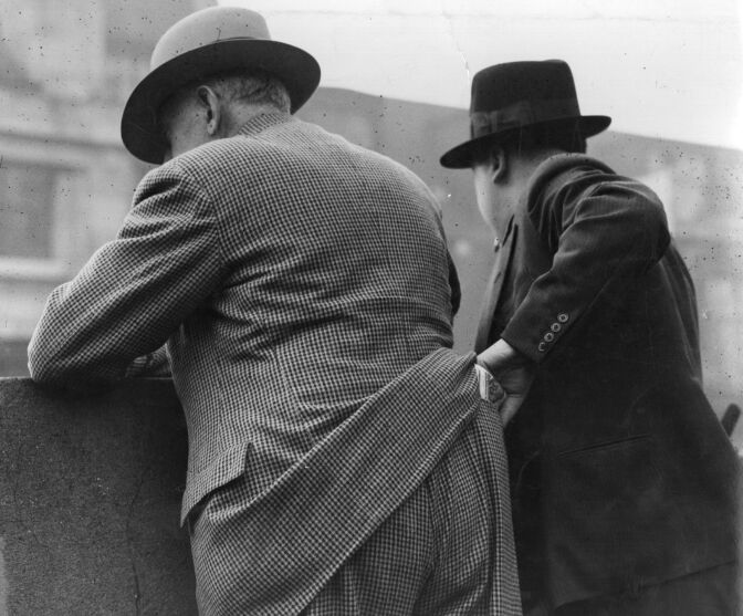 circa 1940: A pickpocket at work in New York. How much do you trust your fellow American?