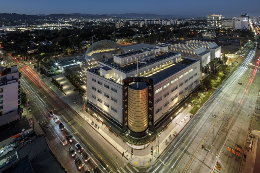 an overhead shot of the buildings at the corner of Wilshire and Fairfax Blvds. at night. In the foreground is the new Academy Museum