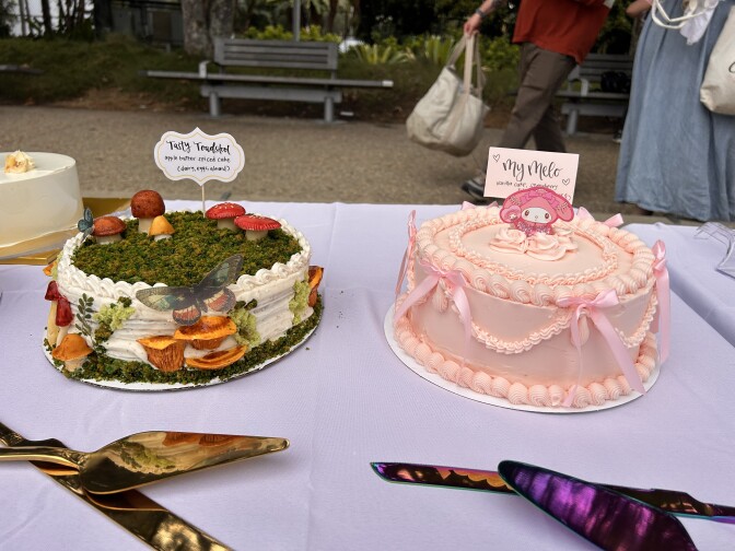 Two beautifully decorated cakes on a table with a lavender table cloth.