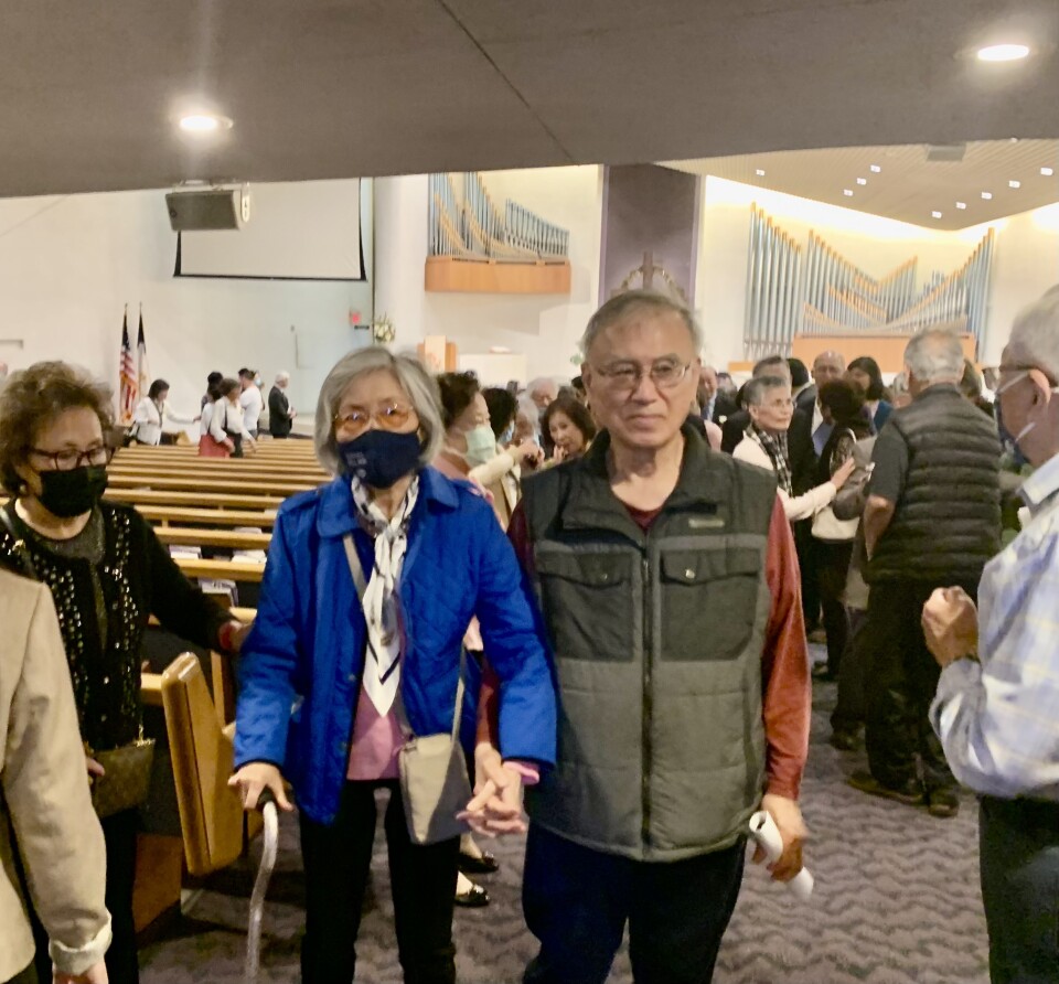 A crowd shot of older Asian adults leaving a church service.