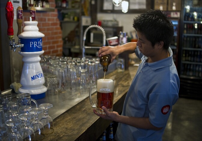 A barman serves Mexican craft beer in a bar in Mexico City, on July 20, 2012. Producers of handcrafted beer make their way in Mexico following the emergence of new breweries in crowded neighborhoods of the capital and as large emporiums producing traditional brands such as Corona stopped being Mexican.