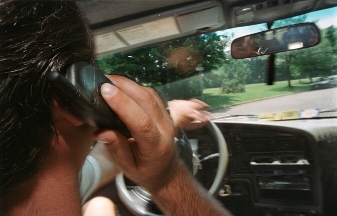 A man uses his cell phone while driving.