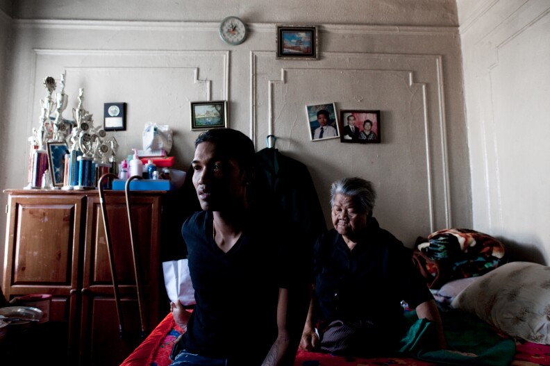 Sovann Ith, 23, sits alongside his grandmother, Somaly Ith, 83, in the living room of their Bronx apartment. The complex was once predominantly Cambodian, but is now home to just five families. Bronx, New York, Sept. 2011.