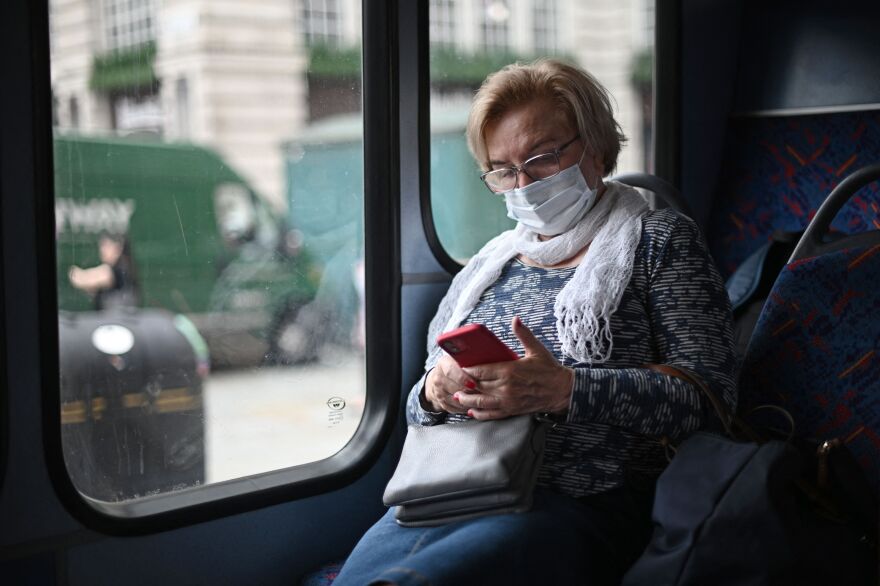 A passenger wearing a protective face covering to combat the spread of the coronavirus, checks her phone while travelling on a bus along Oxford Street in central London on July 5, 2021. - British Prime Minister Boris Johnson on Monday unveils plans to lift most of the latest health restrictions from 19 July, including the mandatory wearing of face coverings in some forms of public transport and shops. (Photo by DANIEL LEAL-OLIVAS / AFP) (Photo by DANIEL LEAL-OLIVAS/AFP via Getty Images)