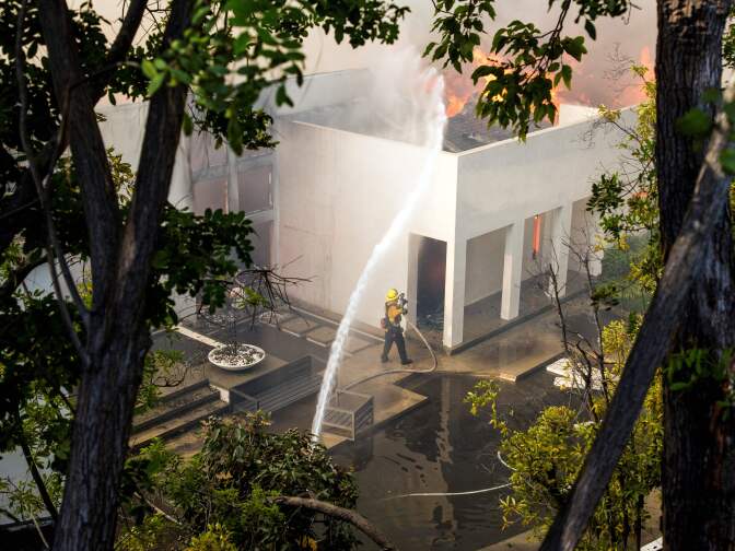 Firefighters work to save burning houses along Linda Flora Drive during the Skirball Fire in Los Angeles, California, December 6, 2017.
The "Skirball" fire ignited before 5 a.m. (1300 GMT) and quickly engulfed some 50 acres, with forecasters predicting the 25-mile-per-hour winds could cause further spreading, threatening multi-million dollar homes and the acclaimed Getty Center museum. / AFP PHOTO / Kyle Grillot        (Photo credit should read KYLE GRILLOT/AFP/Getty Images)