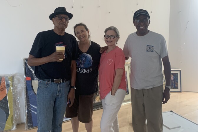 Four animators stand near each other with paintings on the floor in the background.