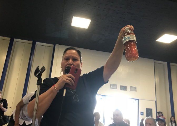 A Sativa water district customer holds up a bottle of the discolored water.