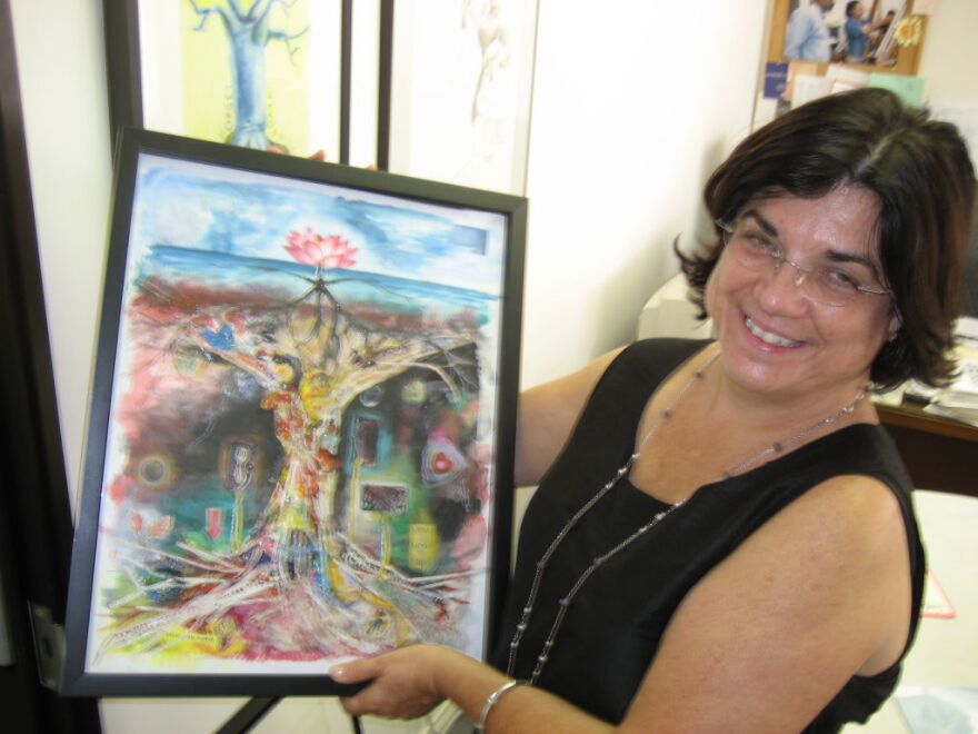 Executive Director Diane Brigham struggles to keep her nonprofit afloat. She holds one of the works of art created by a student who completed Ryman's free fine art Saturday classes. The group received a $26,000 federal stimulus grant to help pay for one of four full-time positions.