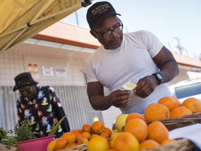 Lou Williams, a regular customer, samples a yellow grapefruit while buying tangerines at the Village Market Place produce stand on Friday, April 10, 2015.
