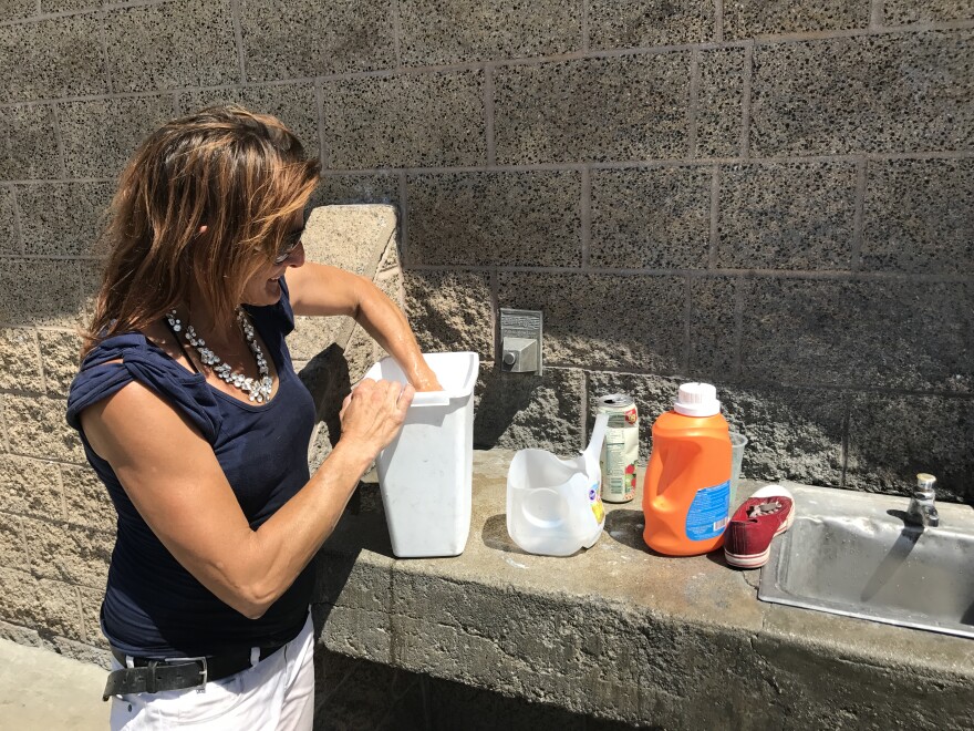 Serena Welch washes clothes outside of public bathrooms near the Santa Ana River in Orange County. She's been living in a tent near the river for four years.
