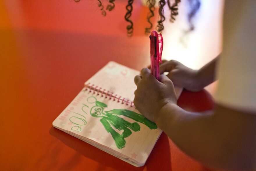 Five-year-old Chloe, daughter of Marie Williams, draws in her notebook on Wednesday evening, June 11 while waiting for her mother to pick her up. Chloe has been coming to the Long Beach day care for about two years.