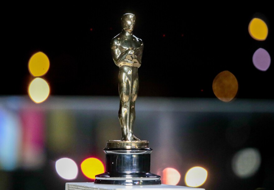 A single Oscar statuette is a gold figure with an angular face and crossed arms.