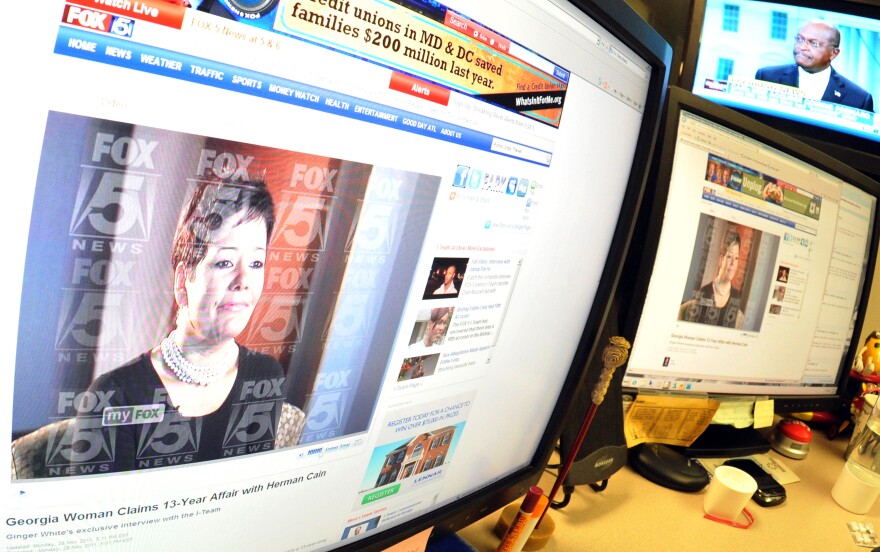 A Fox5 television website displays a photograph of a Georgia businesswoman, allegedly Ginger White, while a live CNN interview shows Republican presidential candidate Herman Cain as seen in an office in Washington, DC on November 28, 2011. Cain said Monday that a woman was set to go public with allegations that the two had a 13-year affair, but he denied the claims and said he would stay in the race. Cain said he learned about the accusations by the woman -- the third to go public with claims that the former pizza mogul engaged in sexual impropriety -- after a television reporter in Atlanta told his lawyer about them..AFP PHOTO Mladen ANTONOV (Photo credit should read MLADEN ANTONOV/AFP/Getty Images)