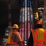 Construction workers look up at the Freedom Tower at the World Trade Center site which is lit in red, white and blue on September 8, 2011 in New York City.