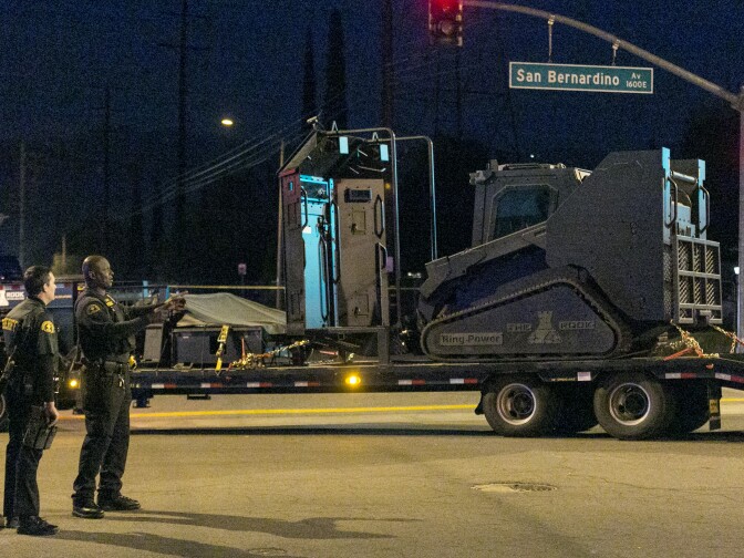 Authorities stand near an armored critical incident vehicle after searching an area near where police stopped a vehicle in San Bernardino, Calif., Wednesday, Dec. 2, 2015, following a shooting that killed multiple people at a social services center for the disabled. (AP Photo/Damian Dovarganes)