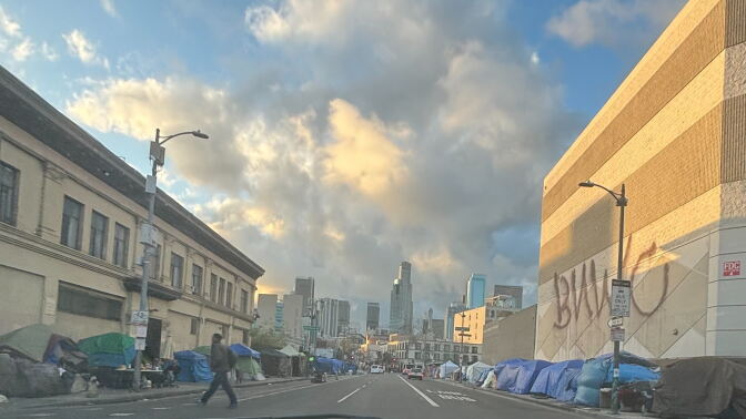 Makeshift tents line with both sides of a city street with tall skyscrapers visible in the background.