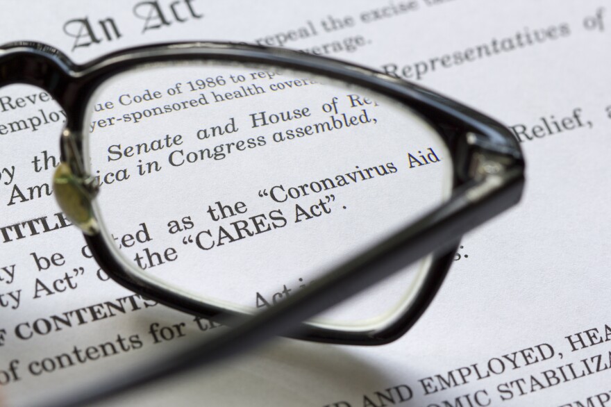 A closeup of the Coronavirus Aid, Relief, and Economic Security Act document with a pair of reading glasses resting on top.