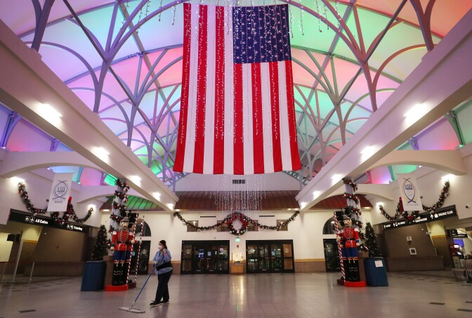 EL PASO, TEXAS - NOVEMBER 12: A worker cleans near an American flag and Christmas decorations in the mostly empty El Paso International Airport amid a surge of COVID-19 cases on November 12, 2020 in El Paso, Texas. Texas eclipsed one million COVID-19 cases November 11th with El Paso holding the most cases statewide. More than 1,000 are hospitalized with COVID-19 in El Paso with around 300 of those patients in the ICU amid a court battle over a shutdown of nonessential businesses. (Photo by Mario Tama/Getty Images)