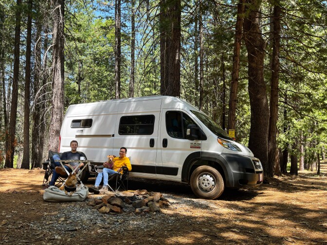 Patrick and Arthur at a campsite with their van and two dogs.