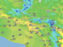 A satellite map includes the Los Angeles, Orange County and Inland Empire areas. The map is colored in shades of yellow, green and blue. Numbers are superimposed on the map to indicate daytime high temperatures. 